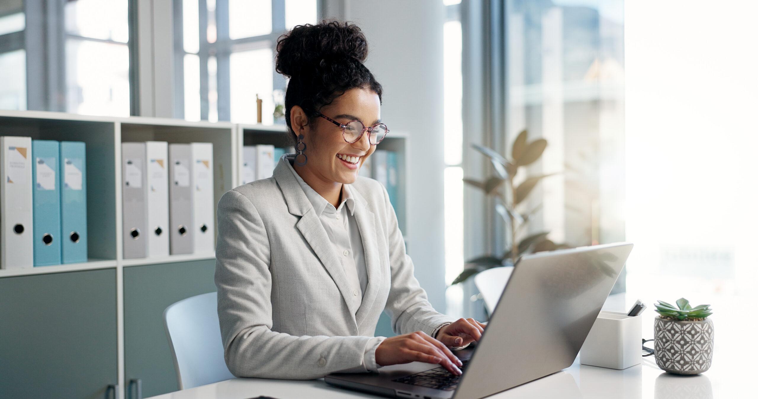 Local government finance staffer smiling while working on a laptop at her office desk